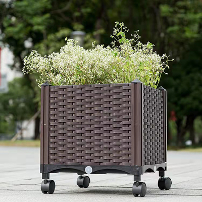 長方形の上げられたプランター箱のStorableプラスチック花箱プランターに水をまいている自己